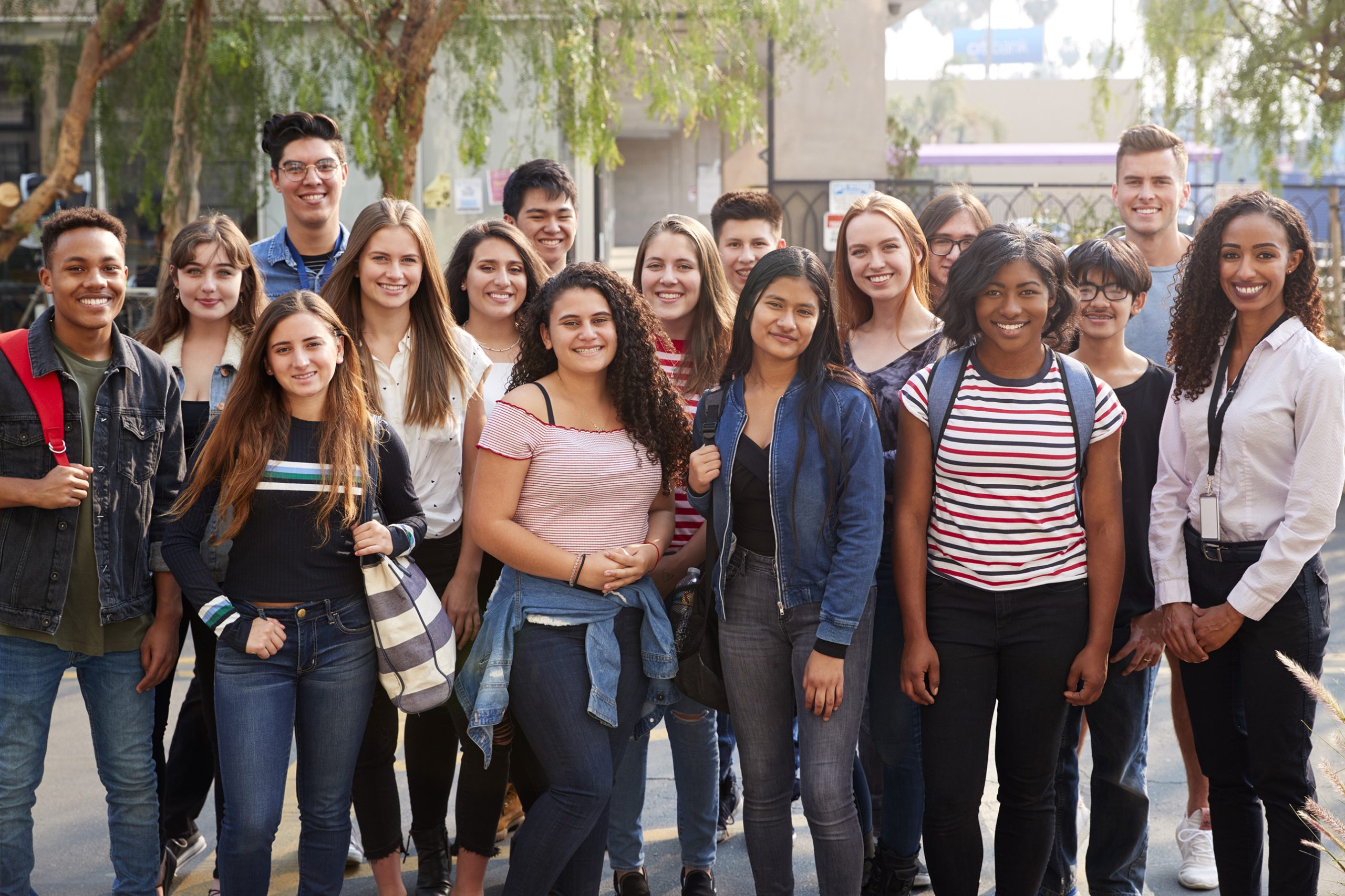 Portrait-Of-Smiling-Male-And-Female-College-Students-With-Teachers-Outside-School-Building-1133755112_3869x2579